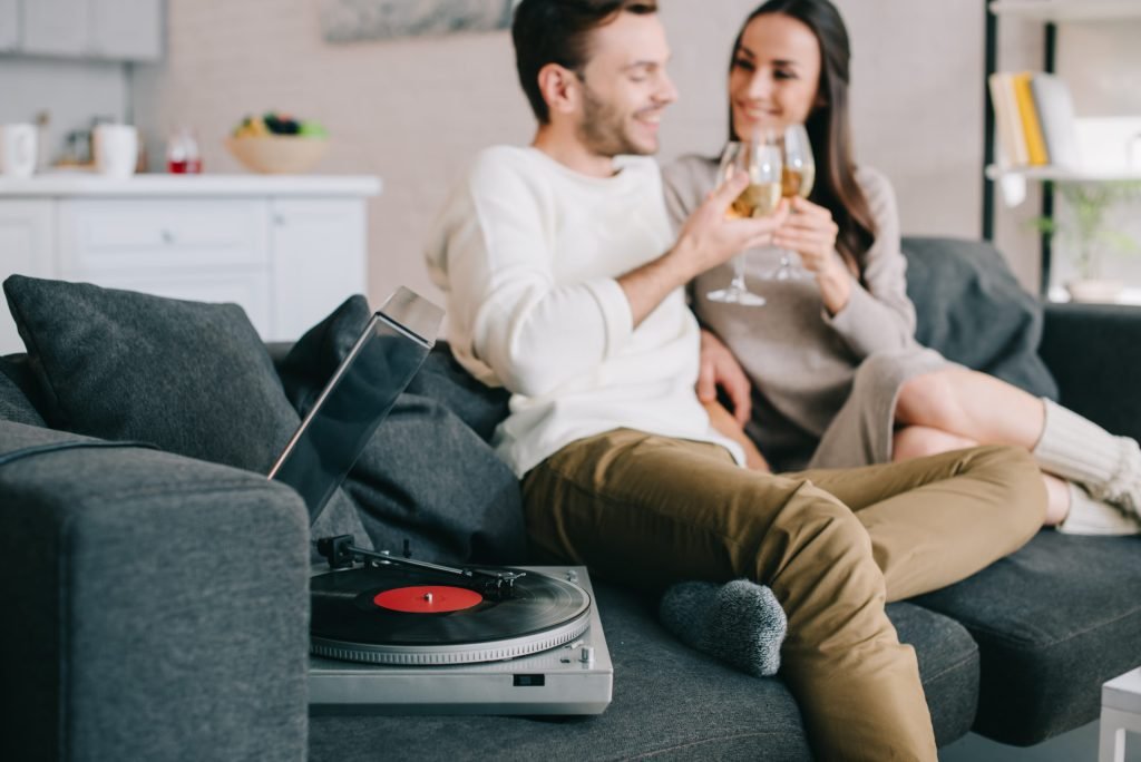 happy young couple listening music with vinyl reco TAUYMM6 scaled 1
